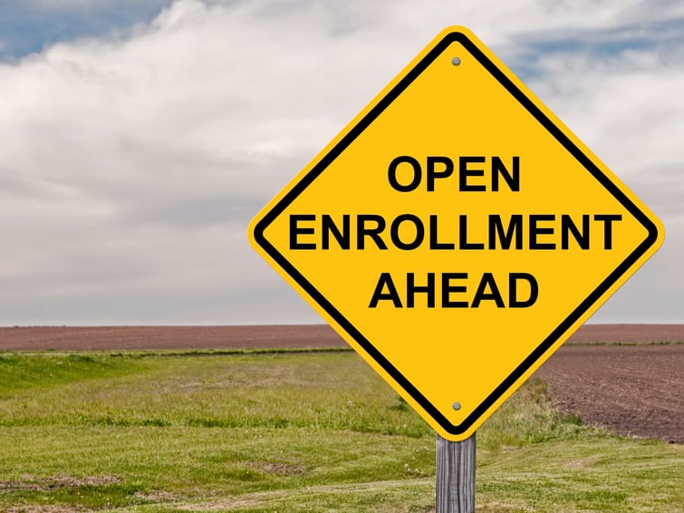 A photo of a yellow street sign advertising benefits open enrollment.