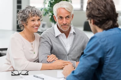 A photo of an older couple meeting with their financial advisor about their retirement options.