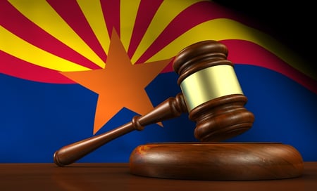 A photo of a judge's gavel in front of the Arizona state flag.