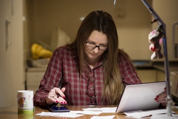 A photo of a woman paying bills after everyone else is in bed.