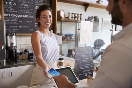 A photo of a coffee shop employee interacting with a customer.