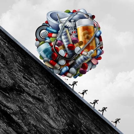cartoon image of pills and syringes compacted into a ball rolling down a hill with people running away.