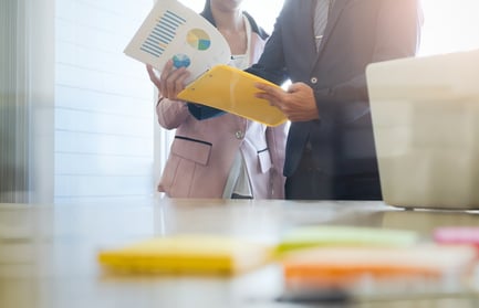 A photo of two people looking at charts and graphs in an office.