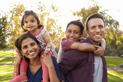 A photo of a husband and wife giving their two children piggy-back rides.