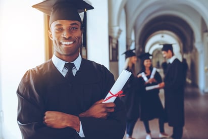 A photo of a man dressed in a cap and gown, holding a rolled diploma.