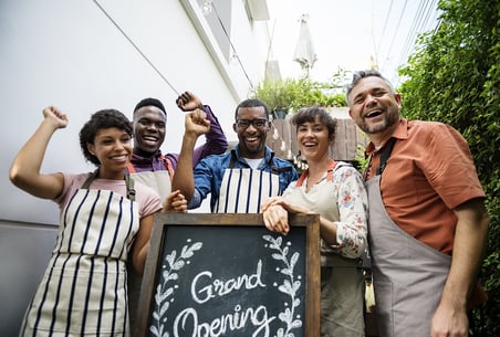 photo of diverse group of people with Grand Opening sign.