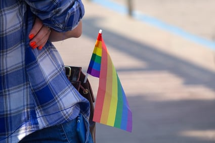 A photo of someone standing with a Pride Flag sticking out of their pocket.