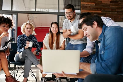 A photo of work group comprised of millennials looking at someone's laptop screen.