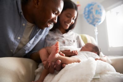 A photo of new parents gazing lovingly at their newborn upon getting home from the hospital.