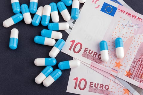 A photo of pharmaceuticals on a table next to european currency.