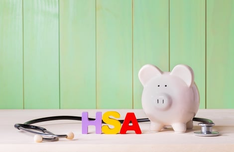 A photo of a piggy bank and a stethoscope with the letters HSA next to them.