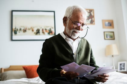 A photo of an older gentleman opening his mail at home.