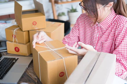 A photo of a woman packing up products to ship to customers.