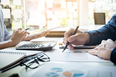 A photo of two people using charts, graphs, and a calculator to make decisions about a group health insurance renewal.