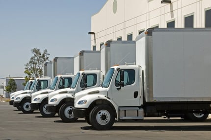 A photo of white trucks lined up and waiting to be loaded with product.