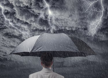 A photo of a man holding an umbrella over his head while a storm rages above him.