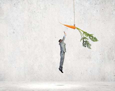 photo of a businessman jumping and reaching for a dangling carrot.